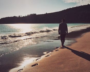 Woman standing on cliff by sea