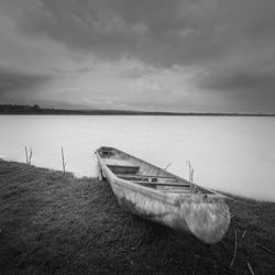 Boat moored at lakeshore against sky