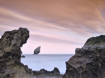 Rock formations in sea against sky during sunset