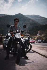 Man riding motorcycle on road against sky