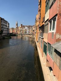 Canal amidst buildings against clear sky