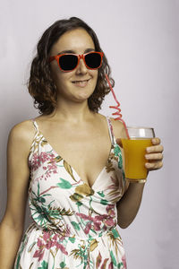 Young woman wearing sunglasses standing against glass