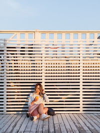 Woman using smart phone against wall