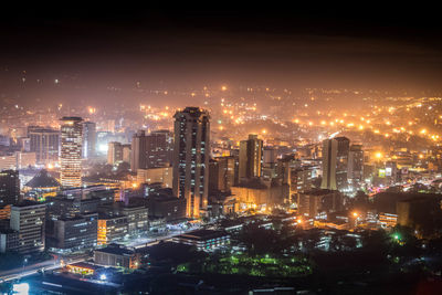 Illuminated cityscape against sky at night