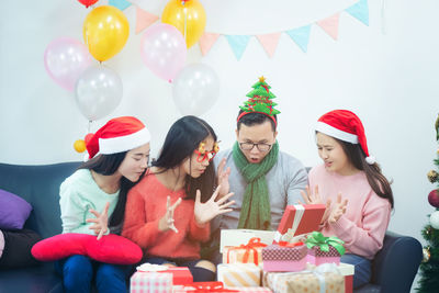 Cheerful family opening gift box while sitting on sofa at home