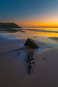 Rock on beach at sunset