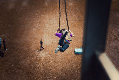 High angle view of woman on swing at playground seen through window