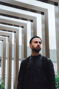 Portrait of young man standing against wall