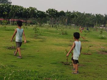 Rear view of boy running on grassy field