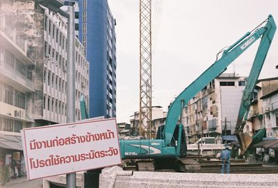 Information sign by buildings in city against sky