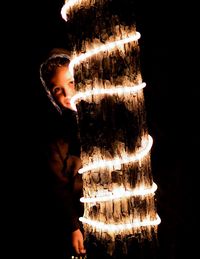 Close-up of young woman standing against black background