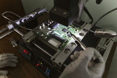 Electronics expert examining damaged circuit board at repair shop