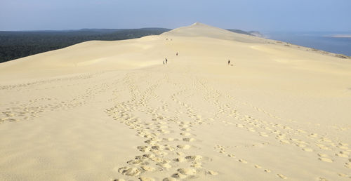Footprints at dune of pilat against clear blue sky