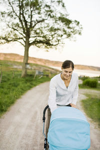 Woman smiling and looking at baby carriage on road