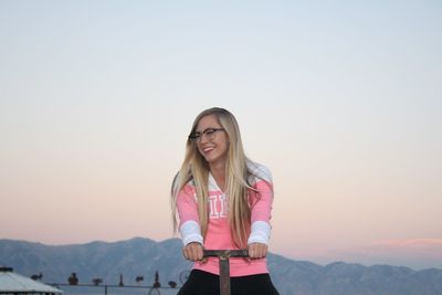 Low angle view of happy young woman on seesaw during sunset