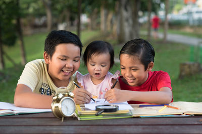 Siblings studying on table in park