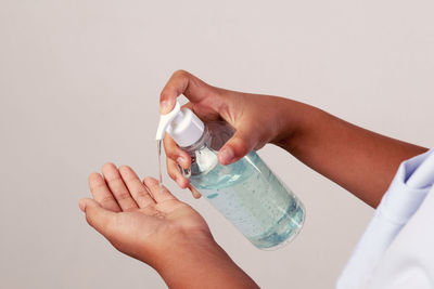 Close-up of woman hand holding bottle against white background