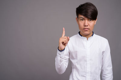 Portrait of man standing against gray background