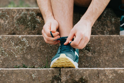 Low section of man tying shoelace on steps