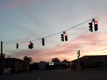 Low angle view of traffic light against sky at sunset