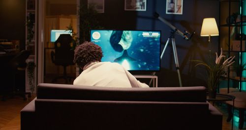 Rear view of woman sitting on sofa at home