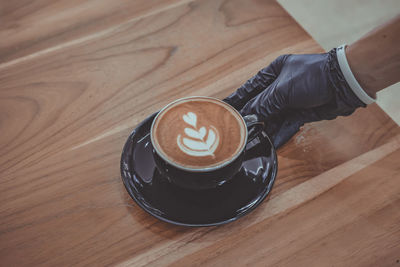 Cropped hand of man holding coffee on table