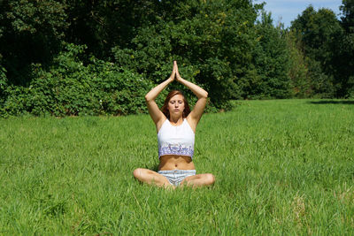 Young woman practicing yoga on grassy field