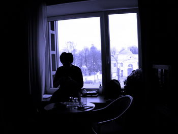 Rear view of boy sitting at window