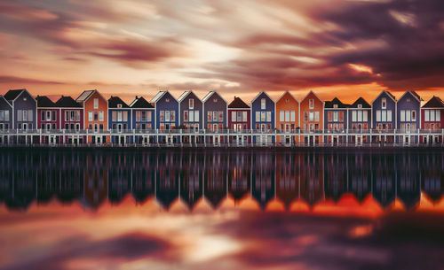 Reflection of building on sea against cloudy sky