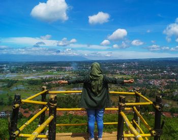 Rear view of woman looking at cityscape against sky