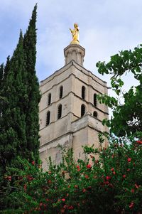 Low angle view of statue by building against sky