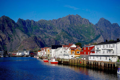 Houses in henningsvaer by sea against mountains at lofoten