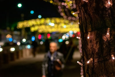 Portrait of man on illuminated tree at night