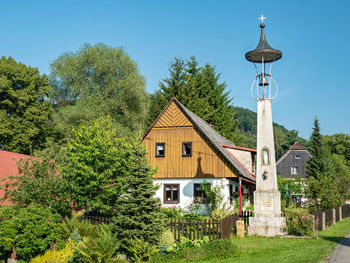 Machovska lhota, czechia. small historical bell tower and typical wooden house in middle of village