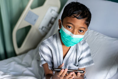 Portrait of senior man holding mobile phone while sitting on bed