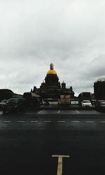 View of vehicles on road against cloudy sky