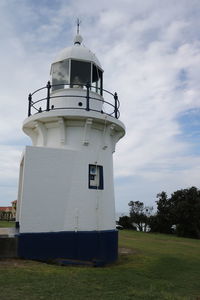 Lighthouse on field against sky