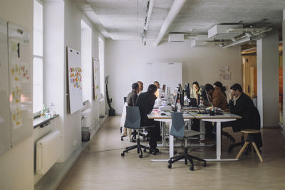 Multiracial phd students with professors sitting at desk in innovation lab