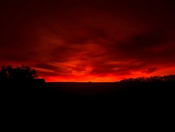 Scenic view of silhouette landscape against orange sky