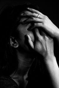 Close-up of depressed woman against black background