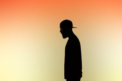 Side view of silhouette man against colored background