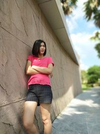 Portrait of young woman standing against wall