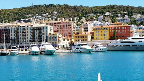 Yachts moored on sea against buildings in town