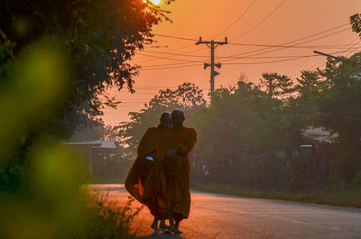 Rear view of man and woman walking on road against sky