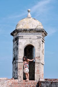 Low angle view of woman at tower against sky