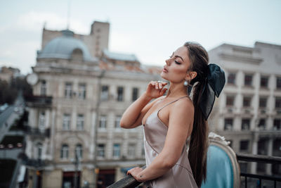 Young woman standing against buildings in city