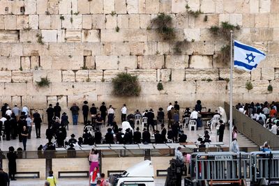 Israel flag waving amidst crowd by wailing wall 