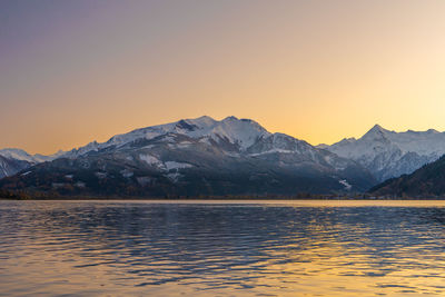 Scenic view of lake by mountains against sky during sunset