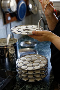 Midsection of person preparing idlis in a kitchen