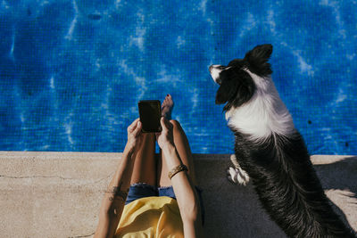 Rear view of woman using smart phone while standing by swimming pool